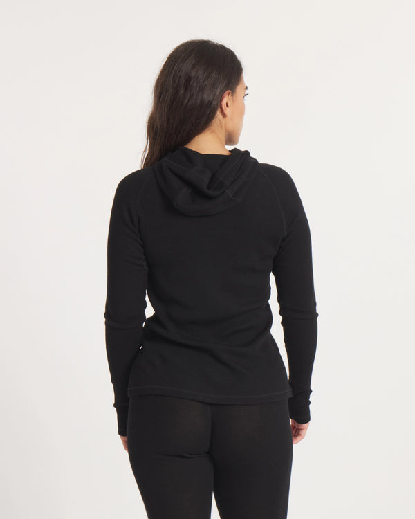 Back view of Women’s Thermal Hoodie in black on model, slim fit showing attached hood and ribbed thermal knit on white background
