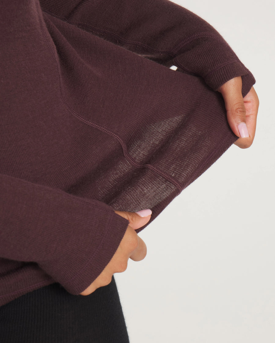Close-up of Women’s Thermal Hoodie in deep plum showing thin, breathable alpaca-merino knit and thumbhole sleeve against a light gray background