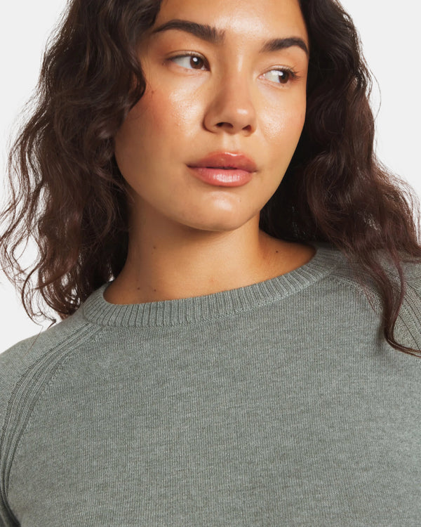 Woman wearing a gray sweater against a white background