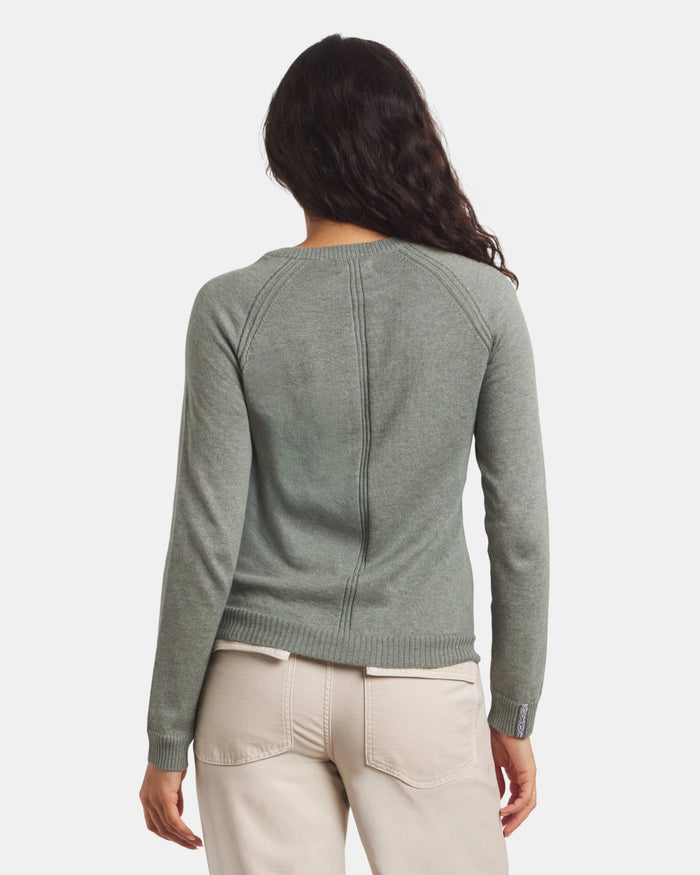 Person wearing a green sweater and beige pants on a white background
