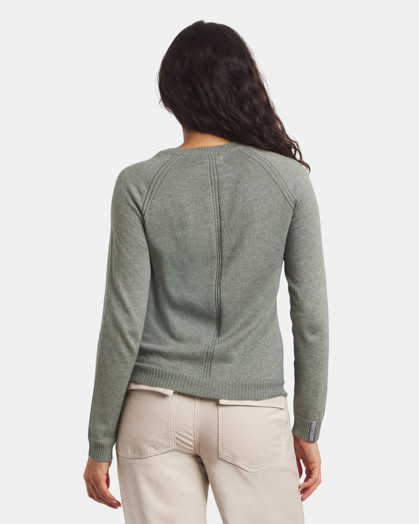 Person wearing a green sweater and beige pants on a white background