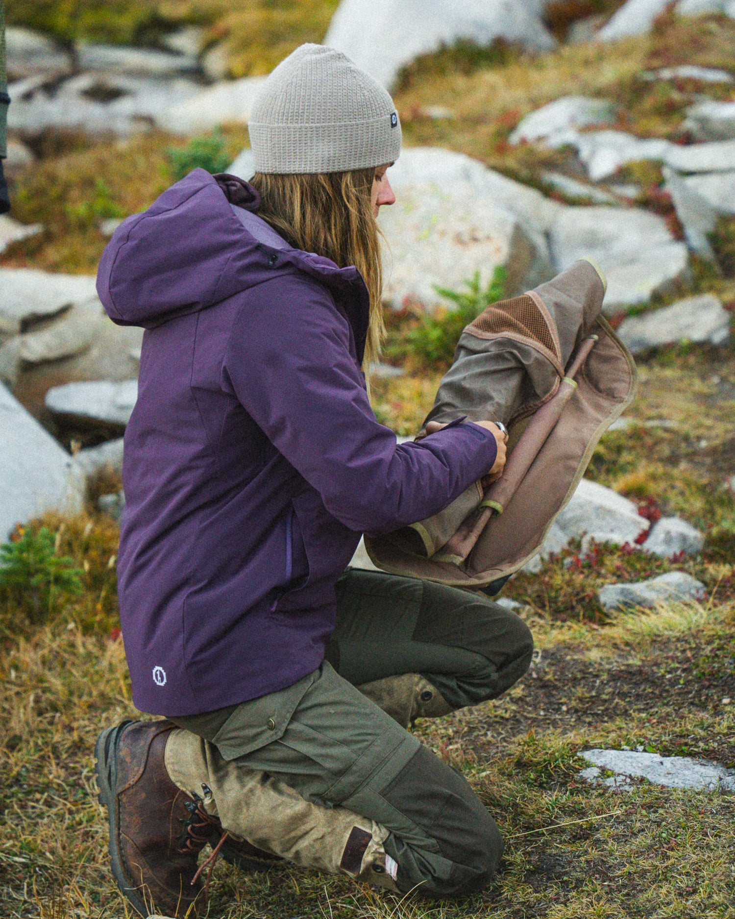 Woman Unfurling Mat Outdoors in Amethyst / Purple Apu Parka Waterproof Jacket – PAKA Apparel