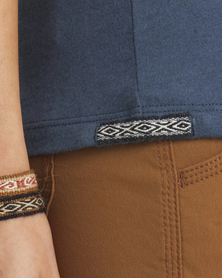 Close-up of Women’s Essential Tee (navy) showing woven Inca ID hem tag and ribbed hem over brown pants