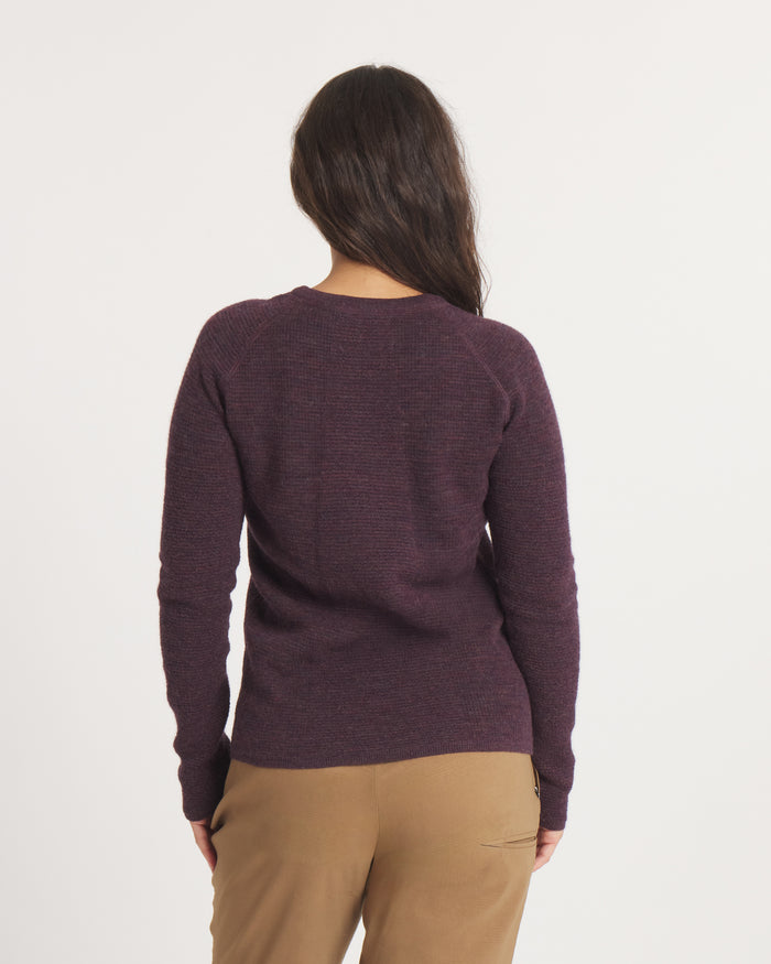 Person wearing the Women's Mountain Crew sweater in Eggplant and brown pants on a white background