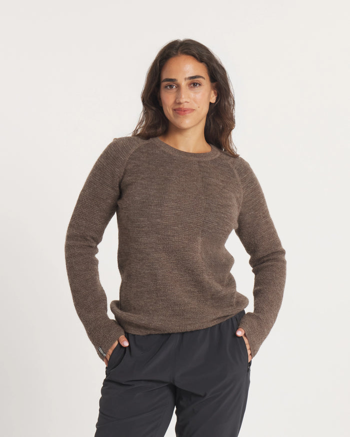 Woman wearing a Women's Mountain Crew sweater in Wood and dark pants on a white background