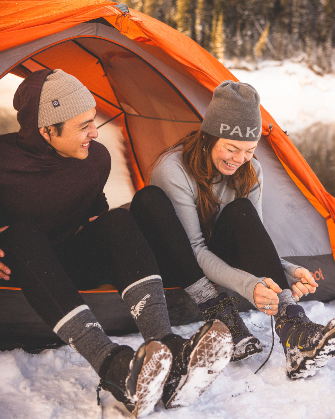 Woman Named Casey in Silver / Light Grey Alpaca Wool Thermal Baselayer Smiling with Man in Tent During Winter – PAKA Apparel