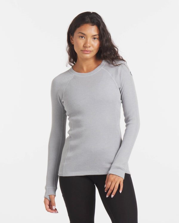 Front of Women’s 1.0 Thermal Crew in light silver, ribbed knit long sleeves and crew neck, roomier fit on model against white