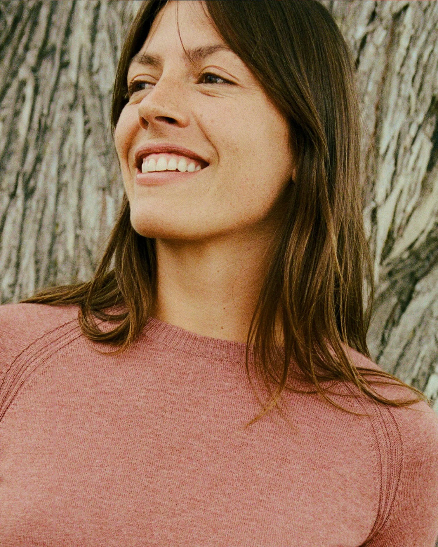 Woman smiling with a tree trunk in the background