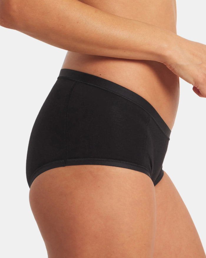 Side view of Women’s Essential Boy Short in black, mid-rise full-coverage fit on model showing flat seams and smooth finish
