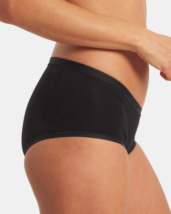 Side view of Women’s Essential Boy Short in black, mid-rise full-coverage fit on model showing flat seams and smooth finish