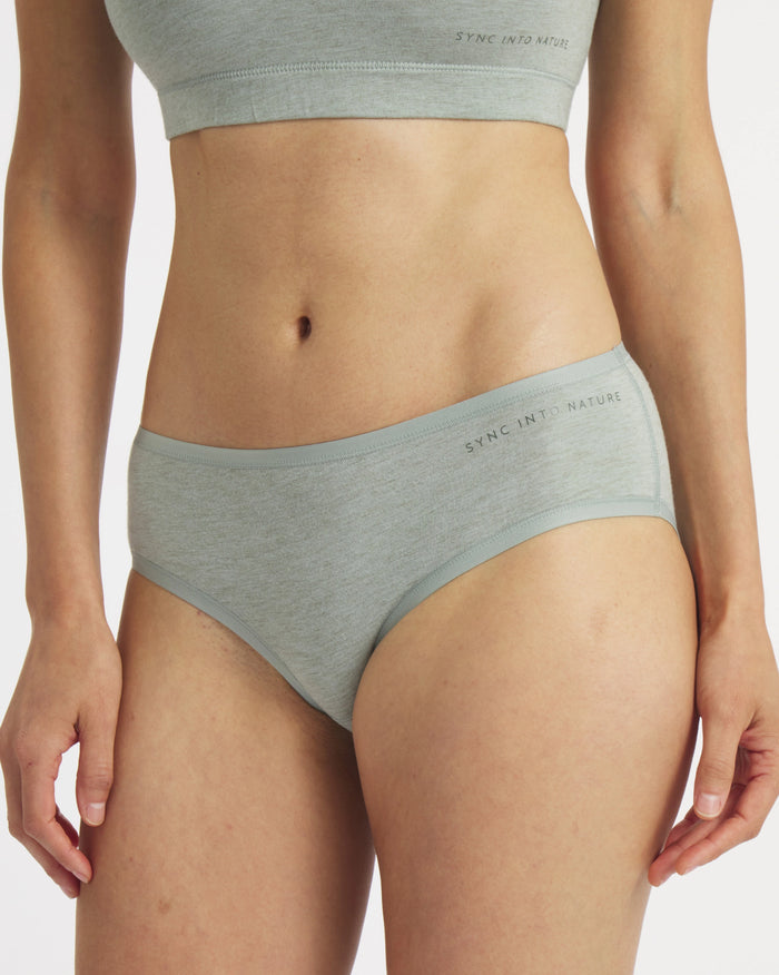 Front view of Women’s Essential mid-rise brief in lichen on model, regular fit showing mid-rise coverage and ‘SYNC INTO NATURE’ waistband text