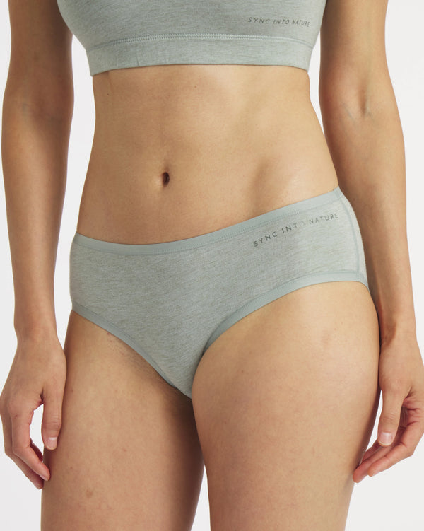 Front view of Women’s Essential mid-rise brief in lichen on model, regular fit showing mid-rise coverage and ‘SYNC INTO NATURE’ waistband text