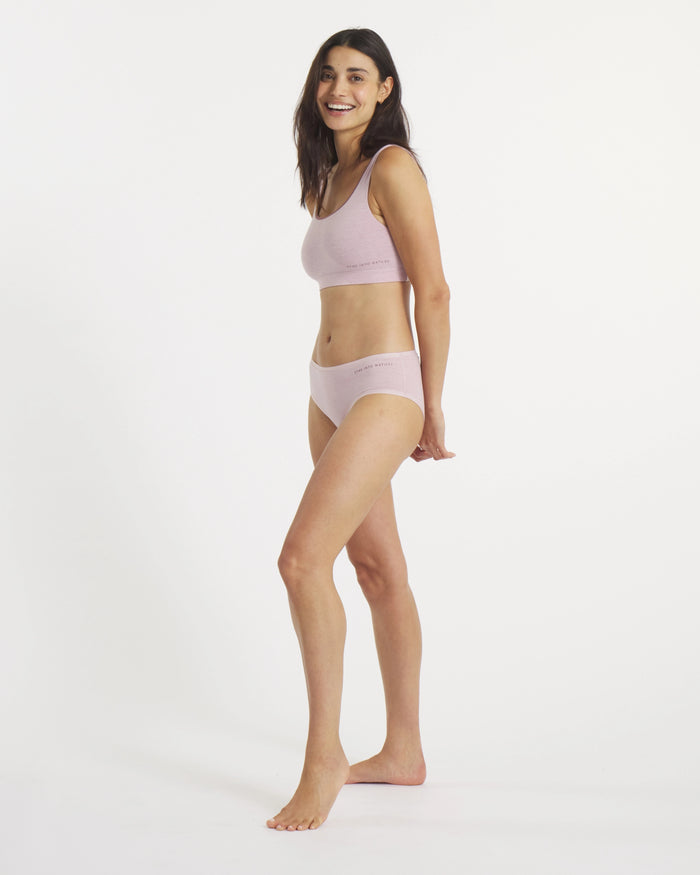Side view of Women’s Essential Scoop Bralette and matching briefs in lilac on a model, showing scoop neckline and elastic logo band on a white background