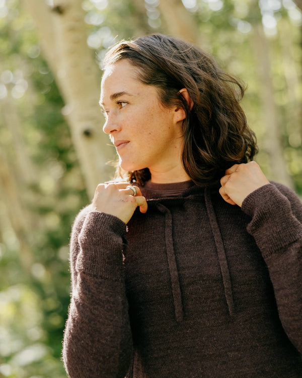 Three-quarter view of women’s alpaca hoodie in fig showing lightweight knit and relaxed fit on model outdoors