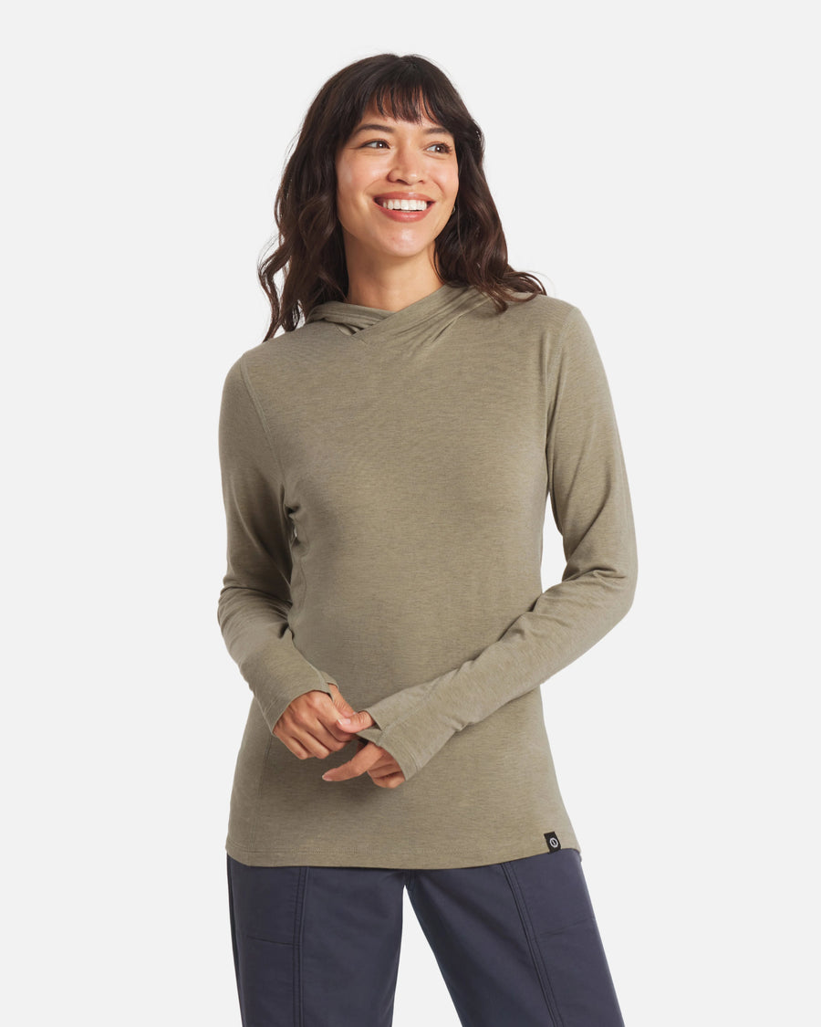 Front view of Women’s Sol Hoodie in elm green on model showcasing long sleeves with thumbholes and slim fit on white background