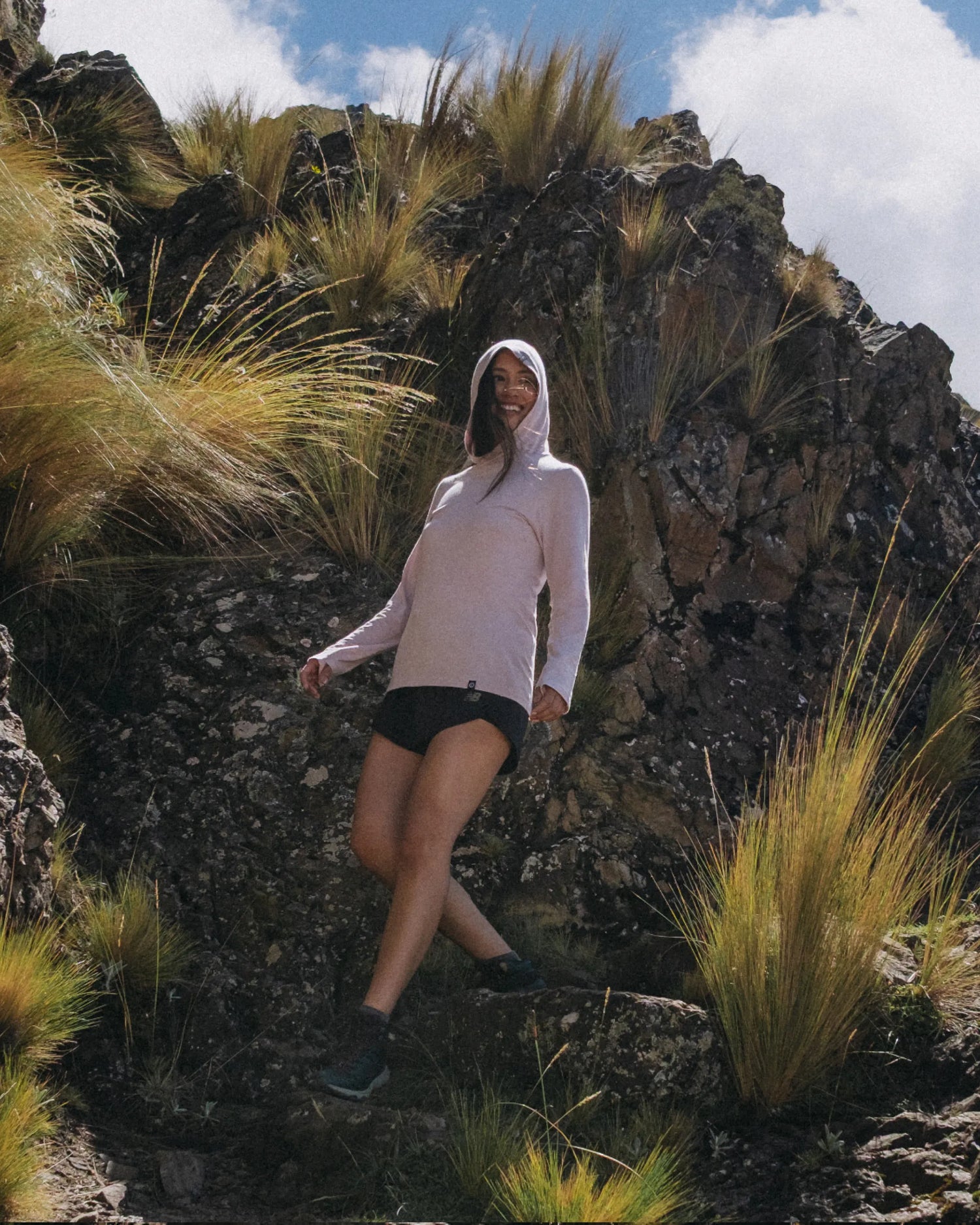 Woman Named Chaska Hiking in Lilac / Light Pink Sol Sun Hoodie with Tall Grass and Rock in Background – PAKA Apparel