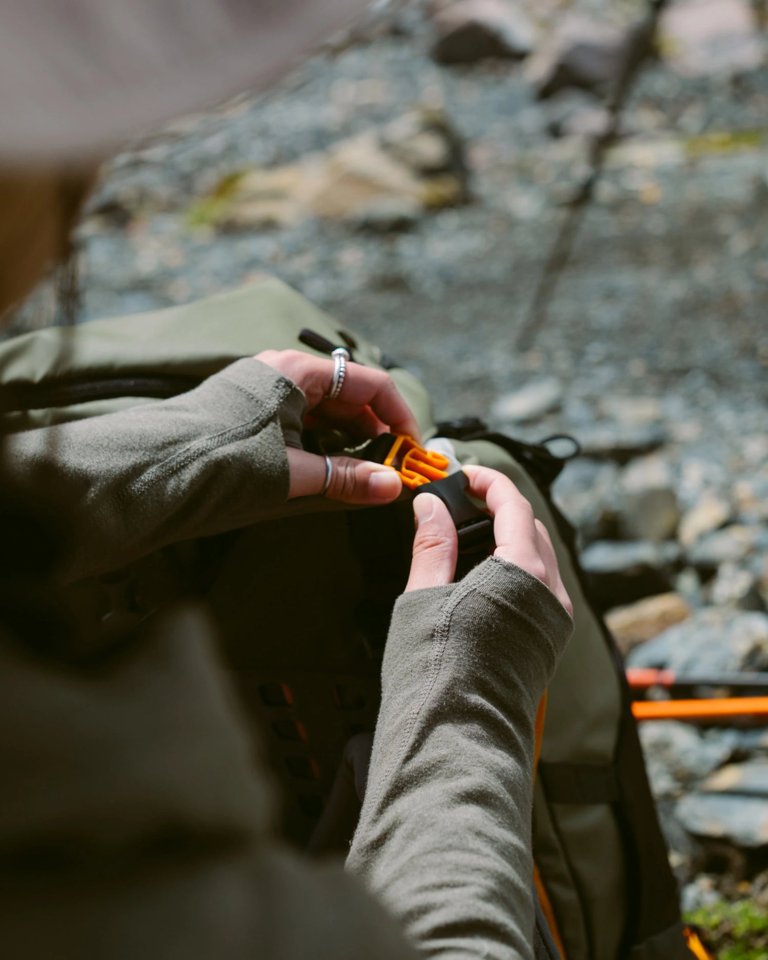 Close-Up of Hands Through Thumbholes of Sol Sun Hoodie Holding Backpack Clip – PAKA Apparel