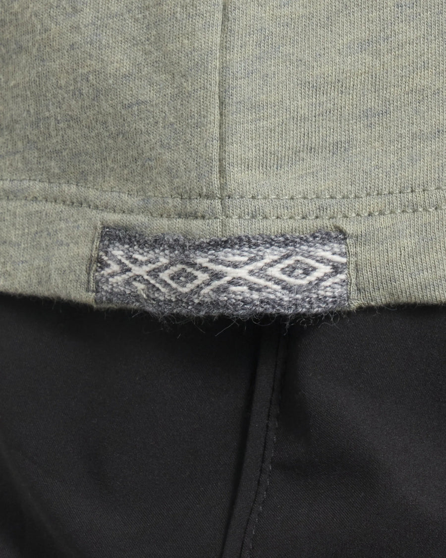 Close-up of Women’s Essential V-neck hem in Balsam showing woven Inca ID label and side seam over black pants