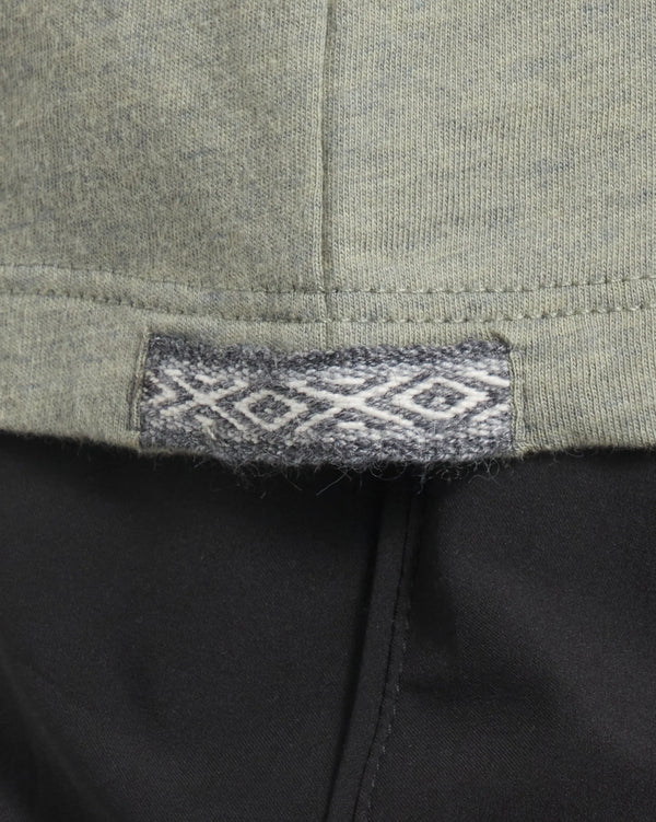 Close-up of Women’s Essential V-neck hem in Balsam showing woven Inca ID label and side seam over black pants