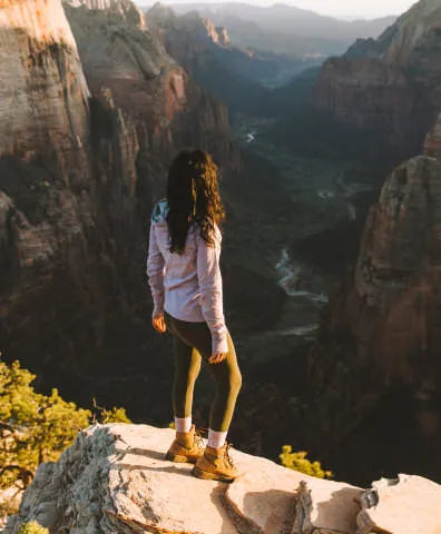 A woman looking down a canyon in her lavender Breathe hoodie