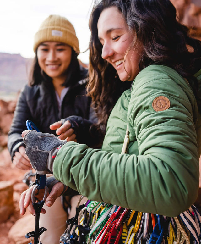 Two women smiling in their Pakafill puffer jackets in front of some rocks