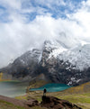 Hiker standing in front of a blue glacial lake at Ausangate