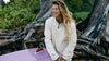 Model wearing cream PAKACLOUD alpaca fleece jacket standing on rocks in a forest setting