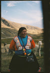 Person in colorful traditional Andean clothing standing in a mountain valley