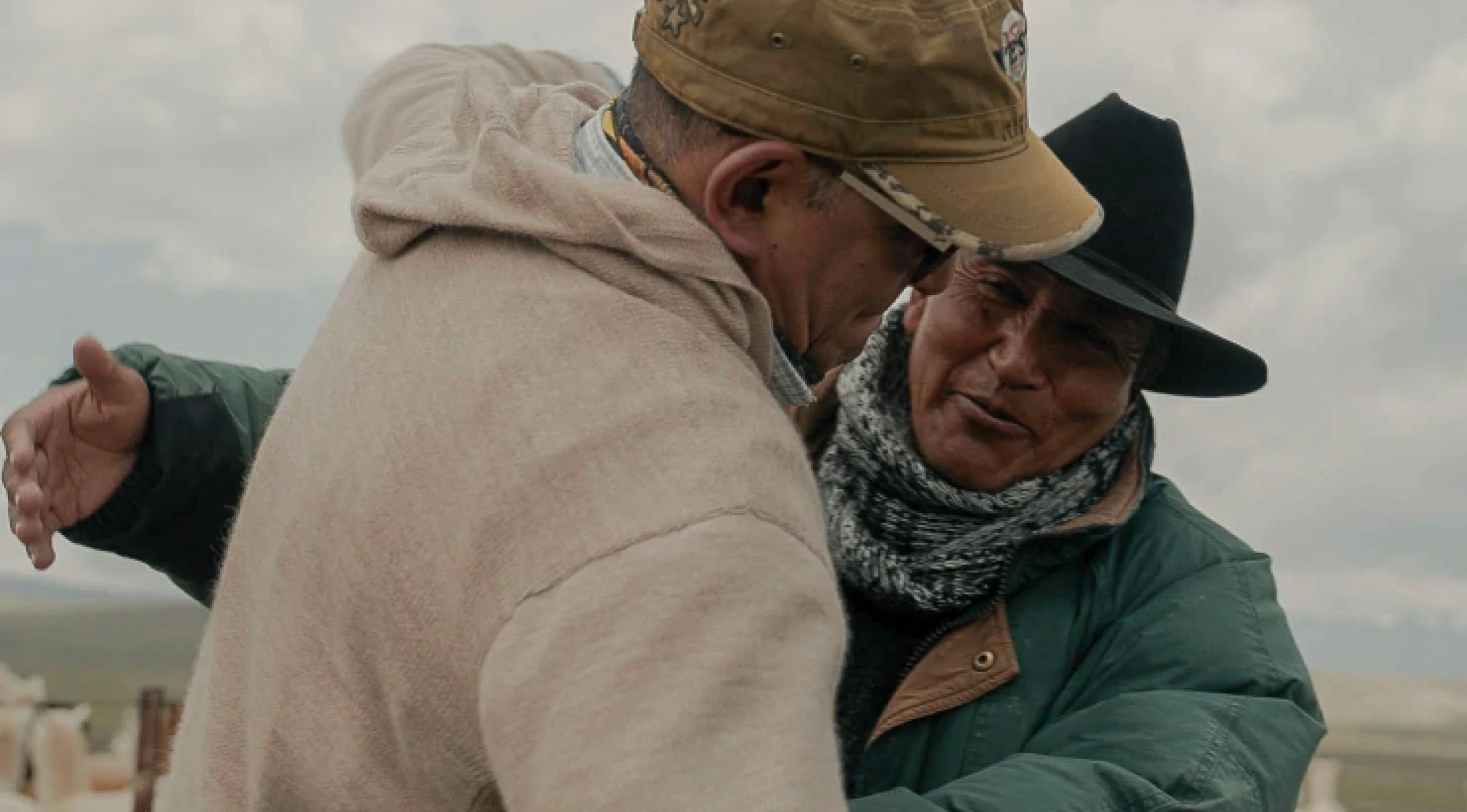 Man wearing alpaca hoodie hugging another man in jacket. 