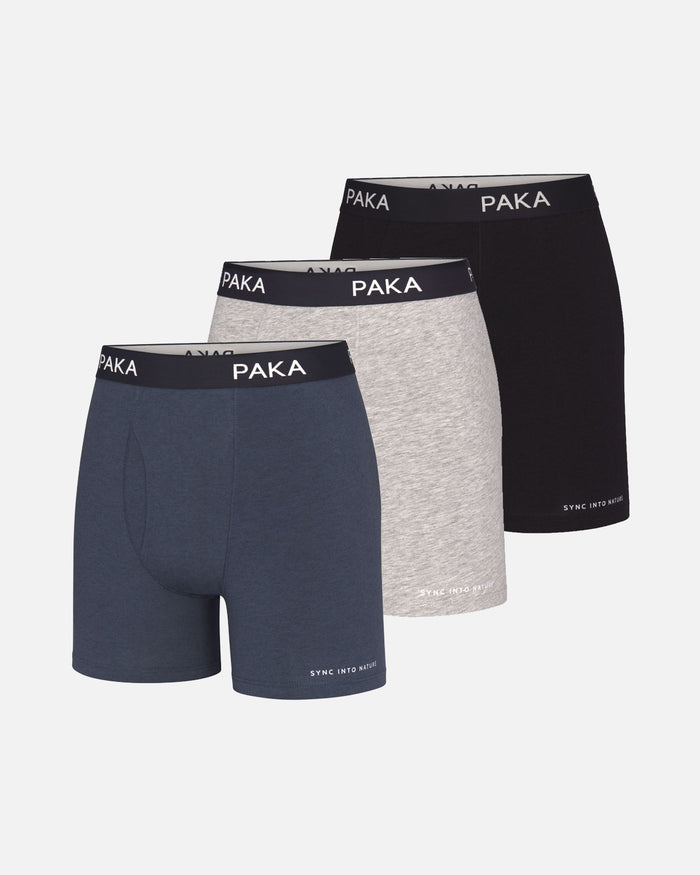 Front view of 3-pack men’s boxer briefs (navy, heather gray, black) showing PAKA branded elastic waistbands on pale gray background