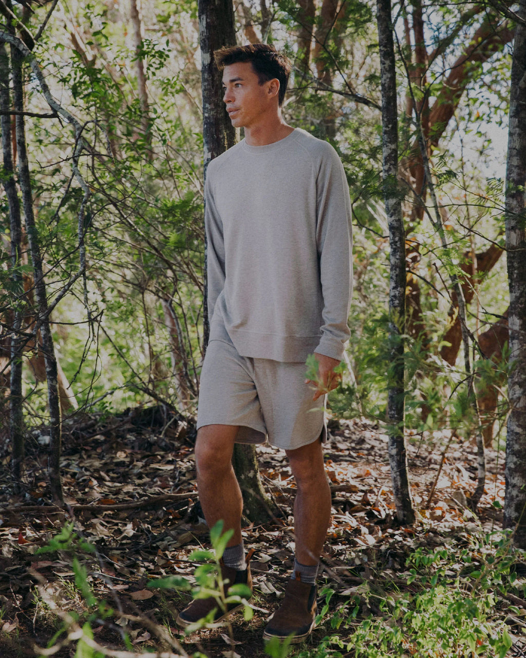 Man wearing alpaca terry crew and terry shorts walking through woods 