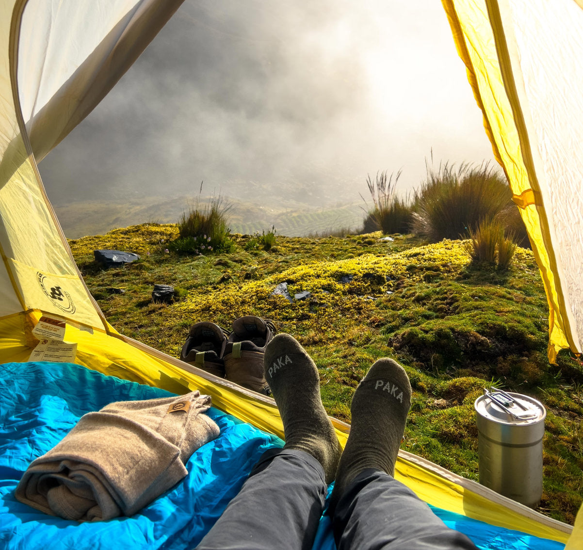 Alpaca socks next to alpaca sweater with view from tent camping 