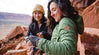 Two women smiling in their Pakafill puffer jackets in front of some rocks