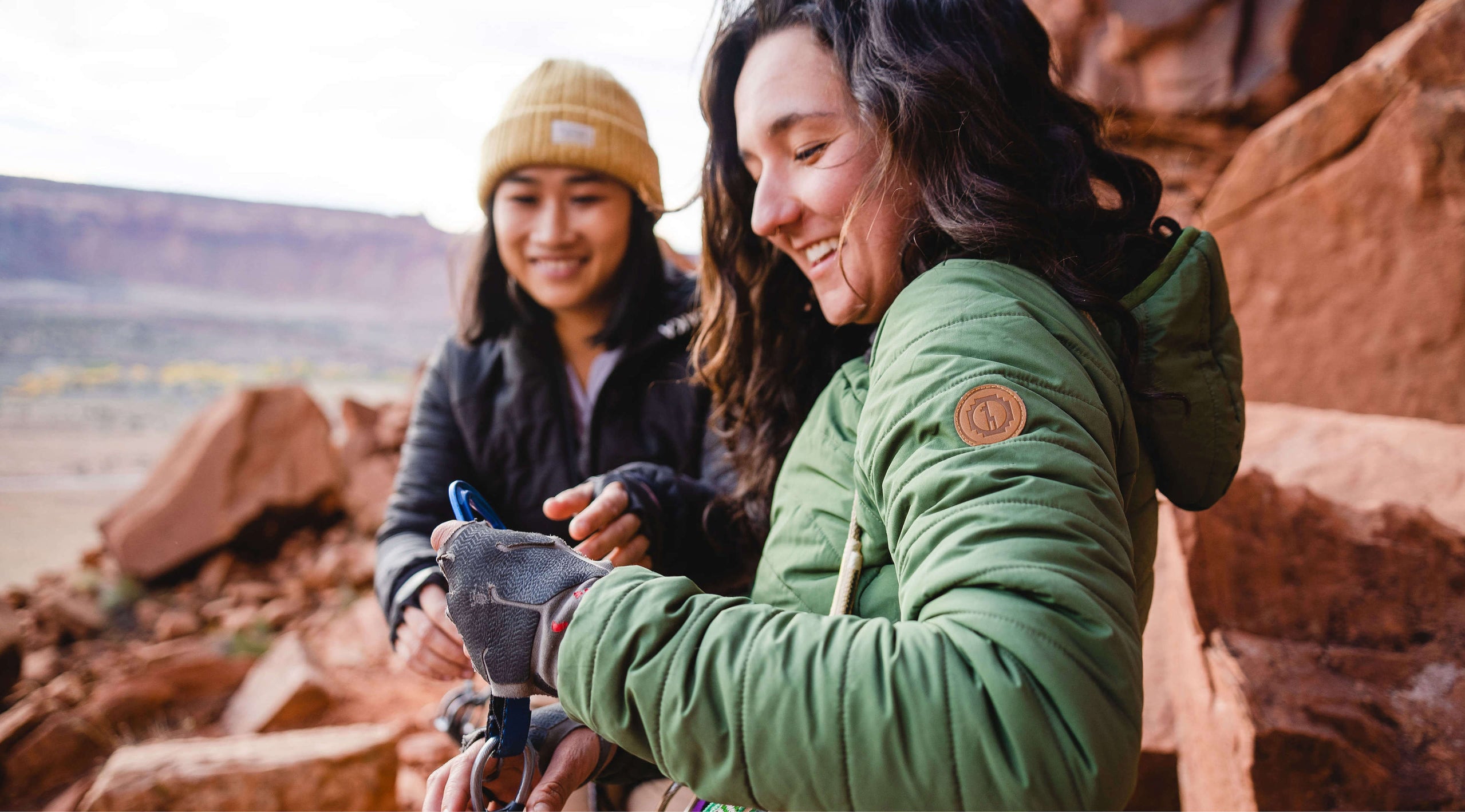 Two women smiling in their Pakafill puffer jackets in front of some rocks