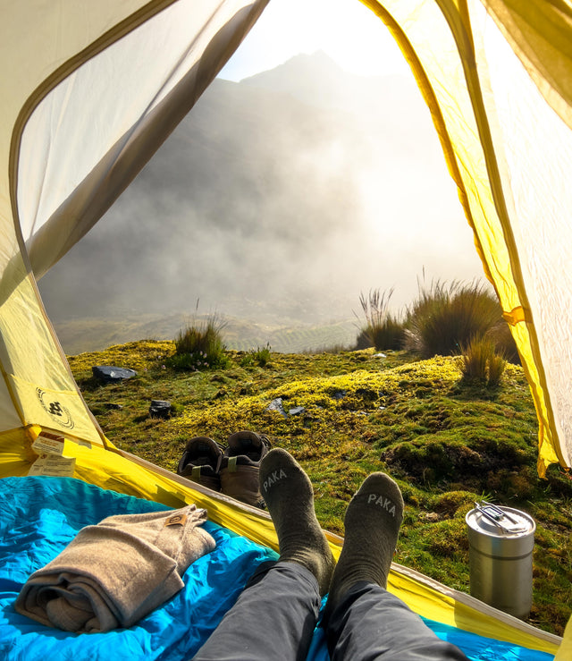 Alpaca socks next to alpaca sweater with view from tent camping 