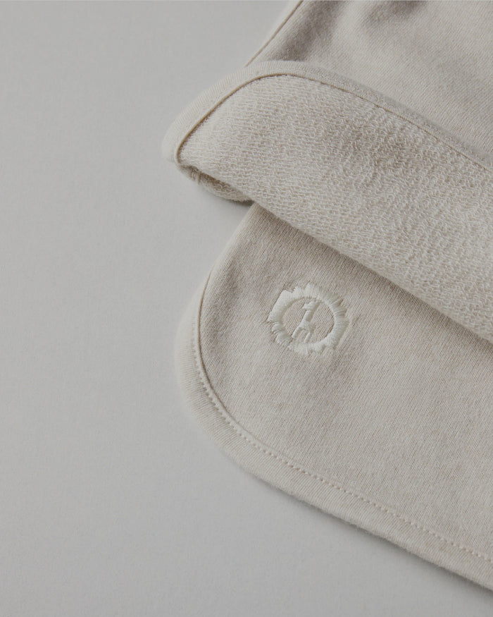 Close-up of Tri-Blend Terry fabric showing looped terry interior and embroidered PAKA logo on light beige background