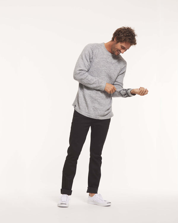 Front three-quarter view of The Costa crewneck sweater in light grey, worn with a drapey fit and showing marled texture and side panel ribbing on a white background