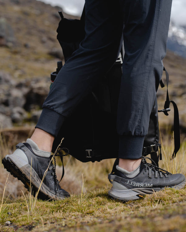 Hiker’s lower legs wearing light gray alpaca ankle socks and gray trail shoes on a grassy mountain trail
