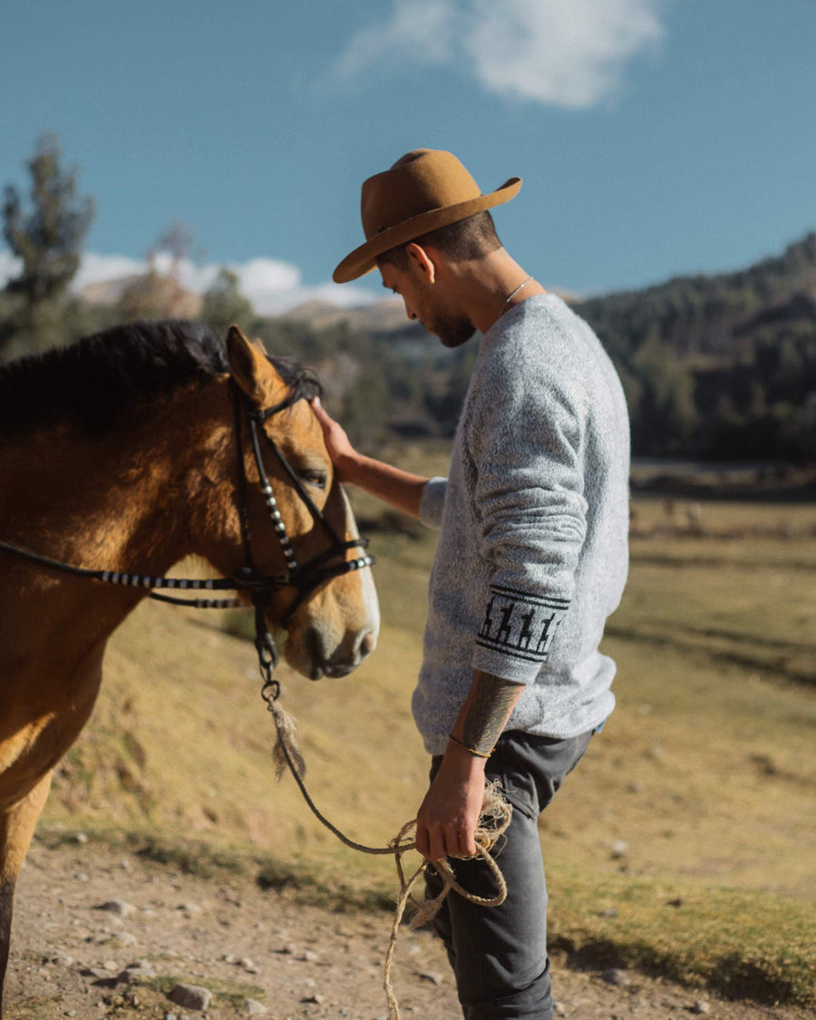 Man wearing costa and petting horse