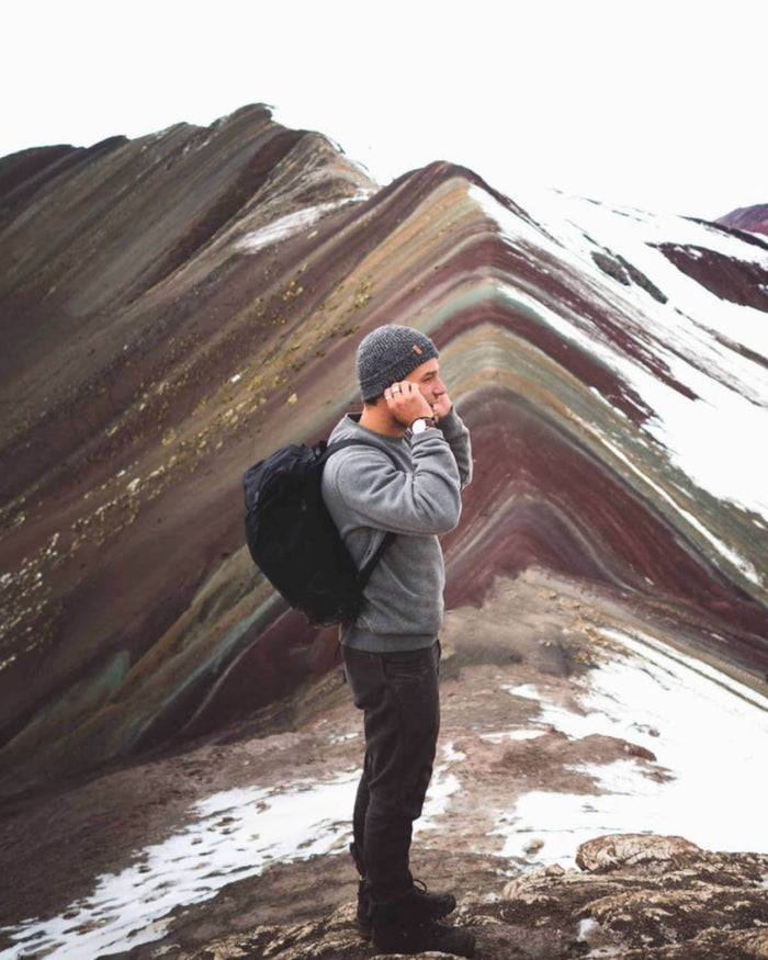 Male Hiker Wearing Charcoal Grey Marled Beanie Alpaca Wool Hat on Rainbow Mountain in Peru – PAKA Apparel