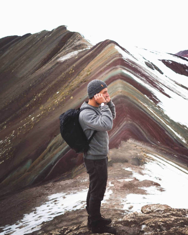 Male Hiker Wearing Charcoal Grey Marled Beanie Alpaca Wool Hat on Rainbow Mountain in Peru – PAKA Apparel