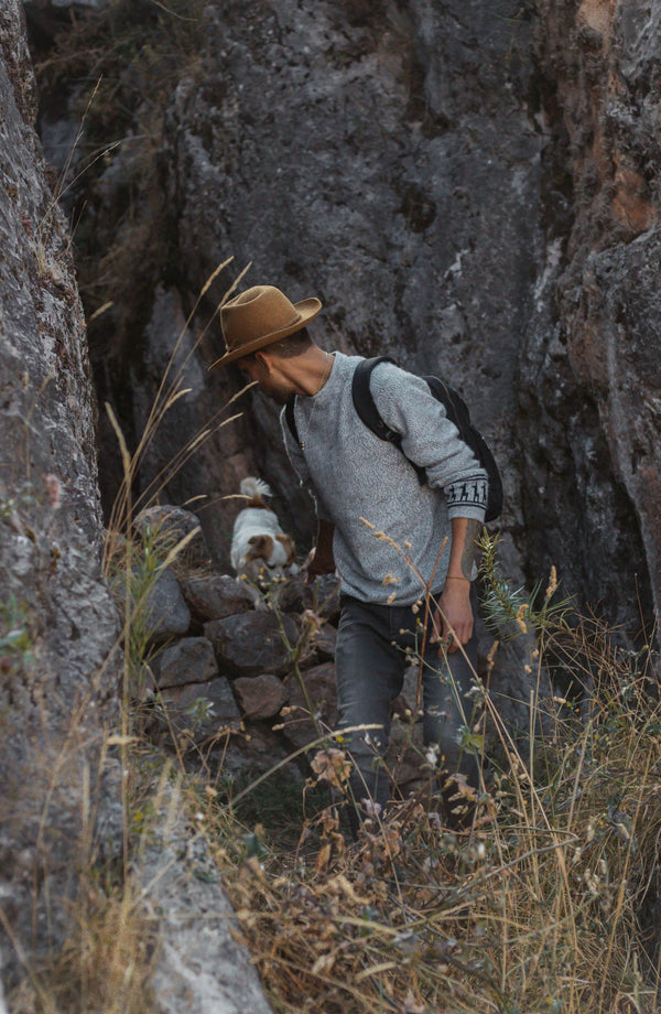 Front three-quarter of The Costa light grey crewneck showing marled texture and side ribbing on a model in rocky canyon
